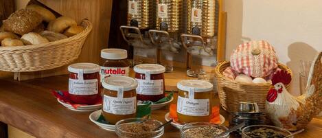 A variety of food items including jars of Nutella, bread, and a decorative chicken figure on a wooden counter.
