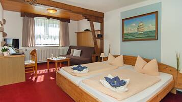 Een kamer met twee bedden, een bureau, een stoel, een televisie en een schilderij van een zeilboot.