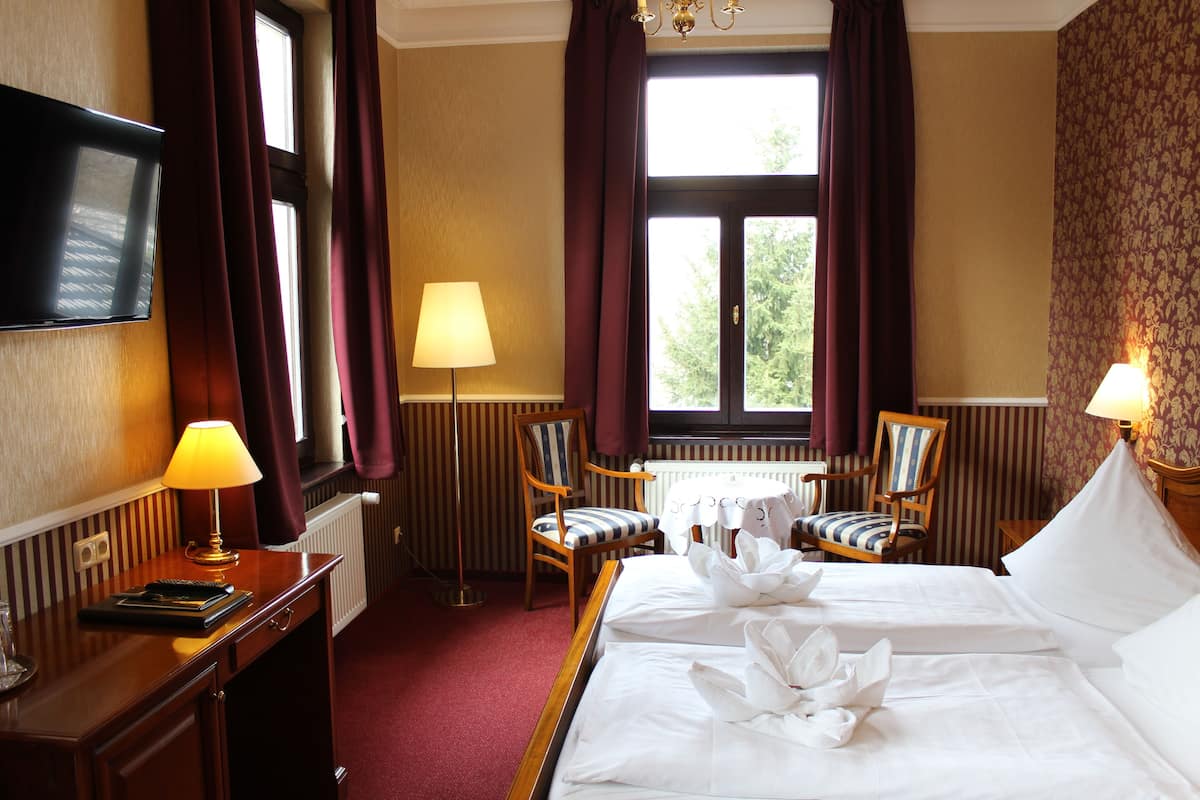 Une chambre d’hôtel avec un lit, deux chaises, une table, un téléviseur et une lampe.
