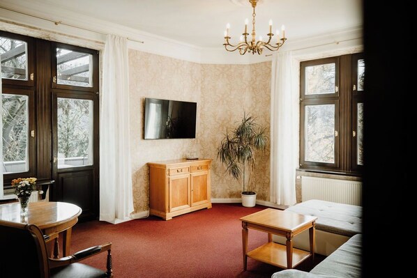 Una habitación con un armario de madera, un televisor, una planta en maceta y un sofá.