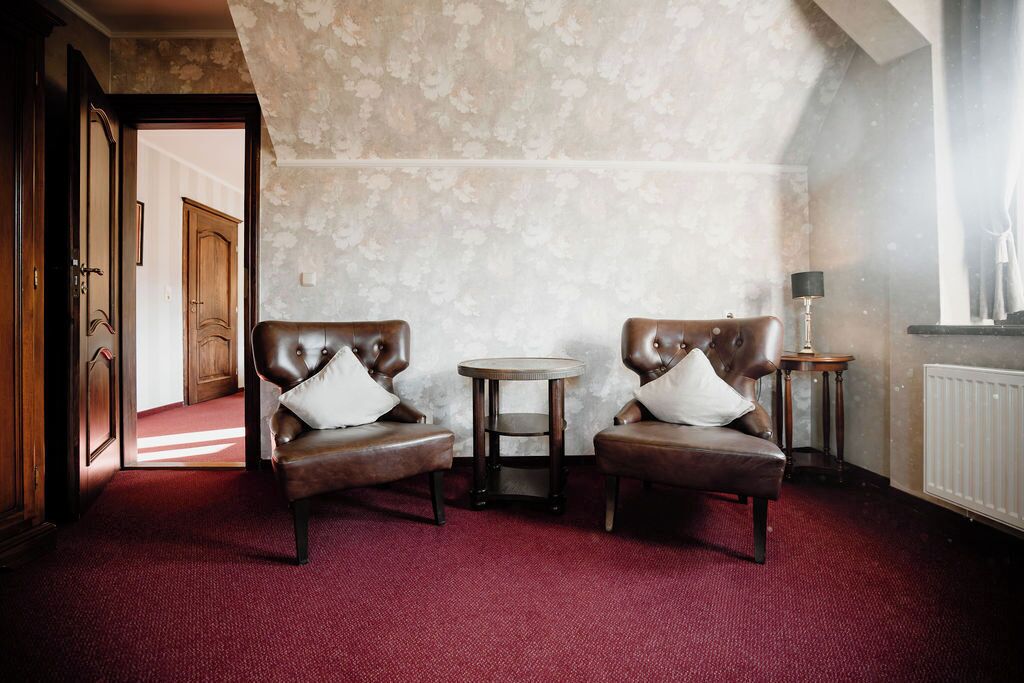 A room with two leather armchairs, a small round table, and a lamp.