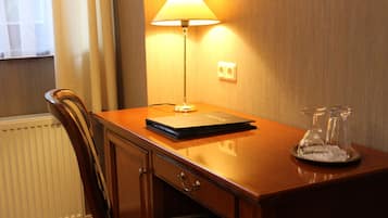 A wooden desk with a lamp, a book, and a glass decanter.