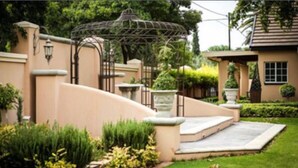 Ein angelegter Garten mit einem Pavillon, einer gebogenen Mauer und einem Weg zu einem Gebäude.
