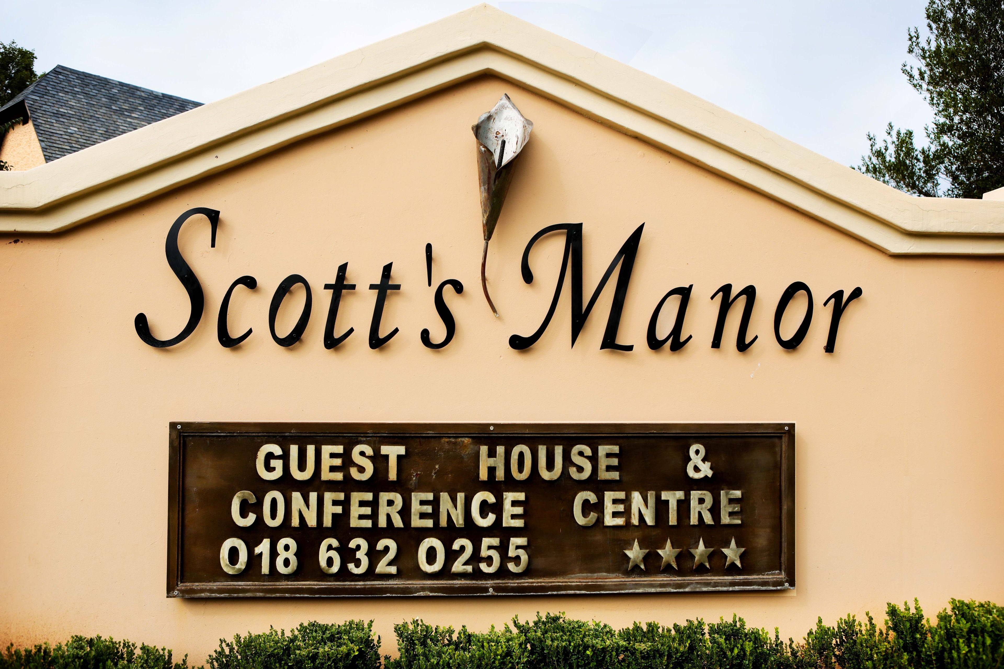 Placa com a inscrição 'Scott's Manor', indicando contato para pousada e centro de conferências.