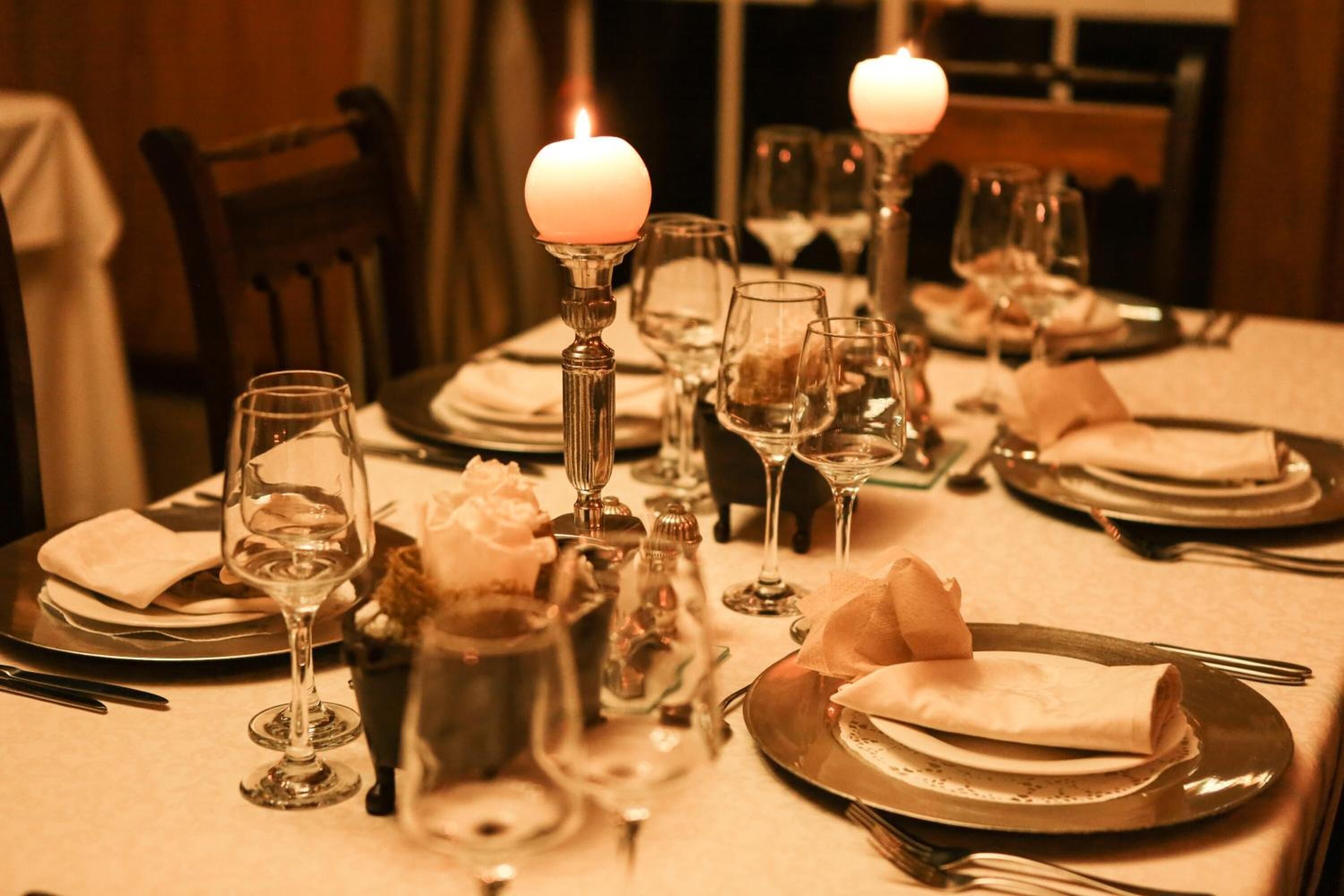 A dining table set with wine glasses, plates, and candles, suggesting a formal dining experience.