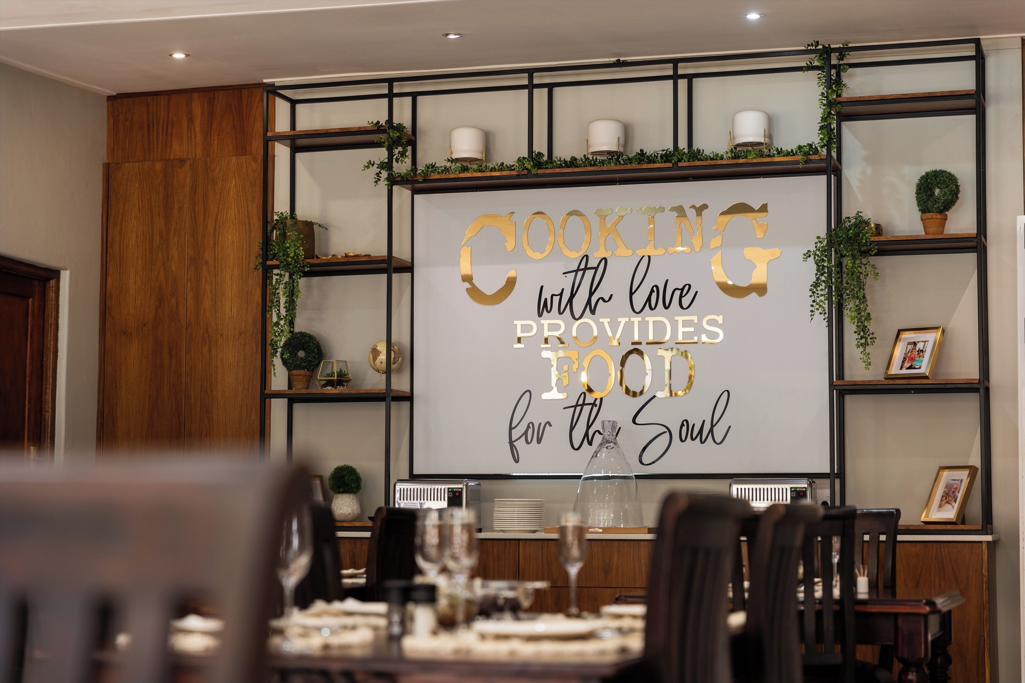 Un coin repas avec une table dressée pour le repas, un mur orné d’une citation inspirante et des étagères décorées d’objets.