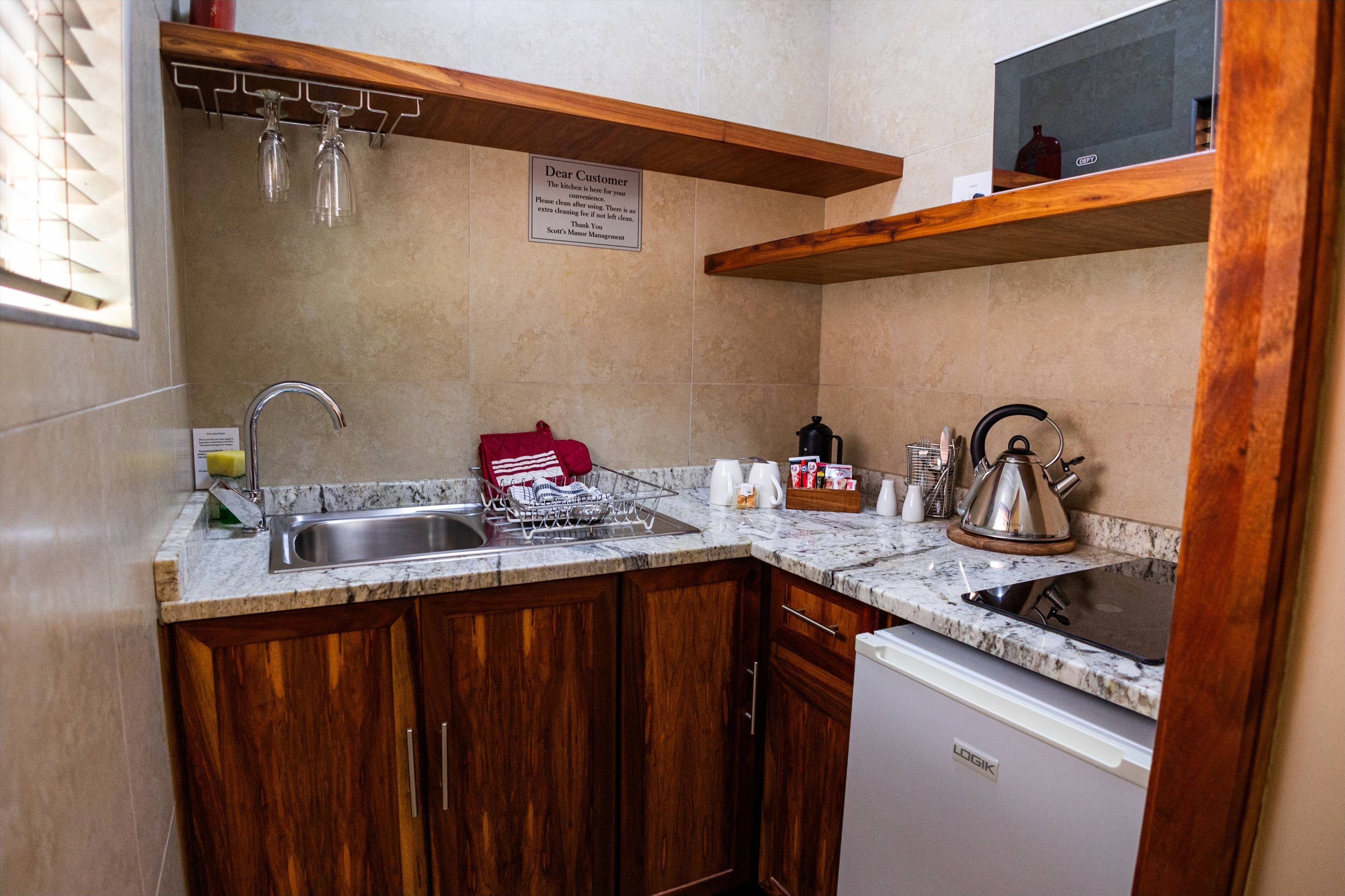 A compact kitchen with wooden cabinets, a built-in dishwasher, a granite countertop, and a stainless steel sink.