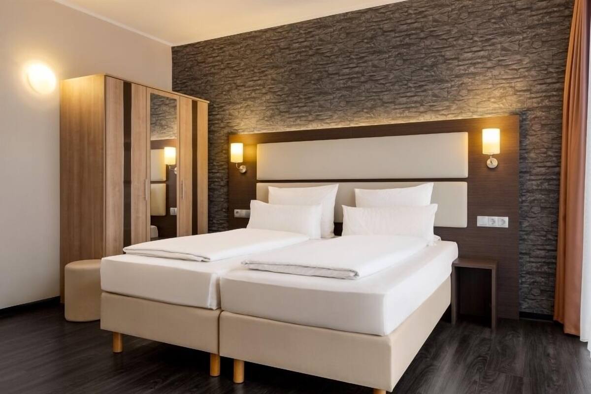 Una cama doble con cabecera, un armario de madera y una pared con textura de piedra.