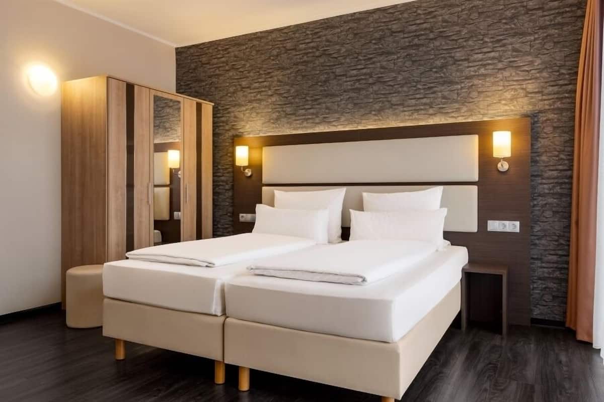 Una cama doble con cabecera, un armario de madera y una pared con textura de piedra.