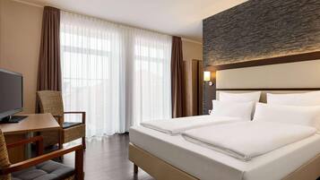 A hotel room with a bed, a desk, a chair, and a television.