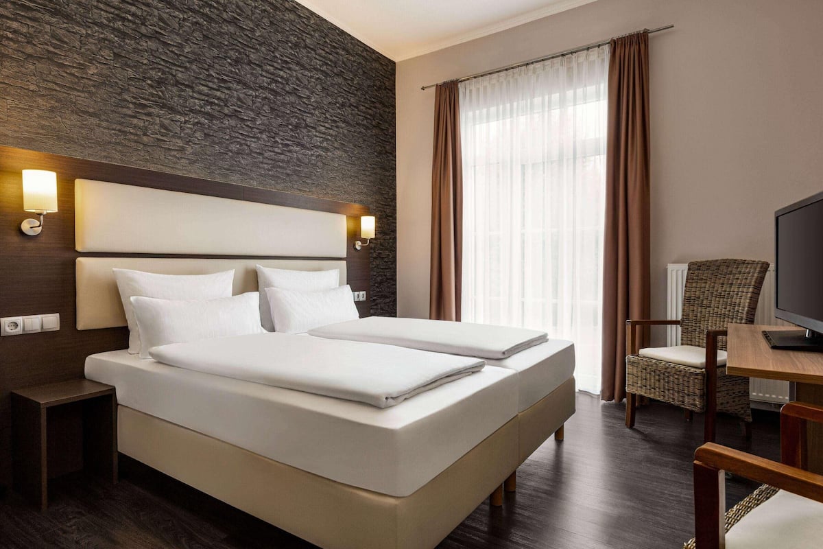 Una habitación de hotel con una cama grande, televisión, una mesita y una silla.