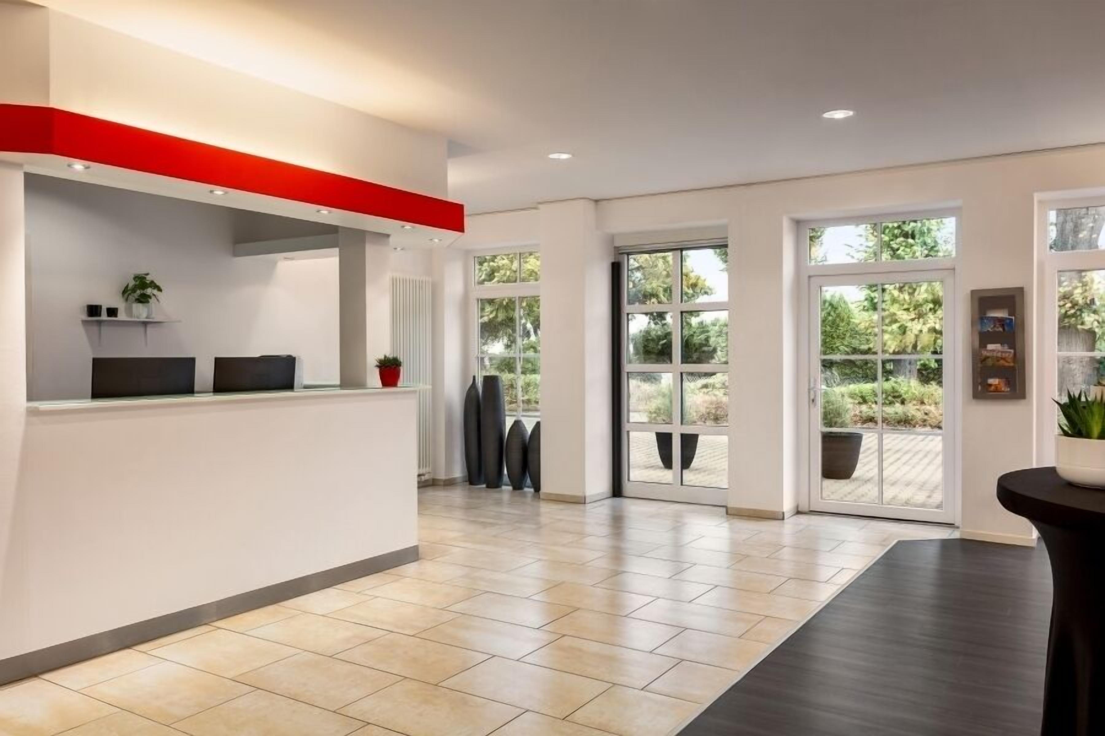 Um hall amplo com balcão de recepção, janelas grandes e vista para o exterior.