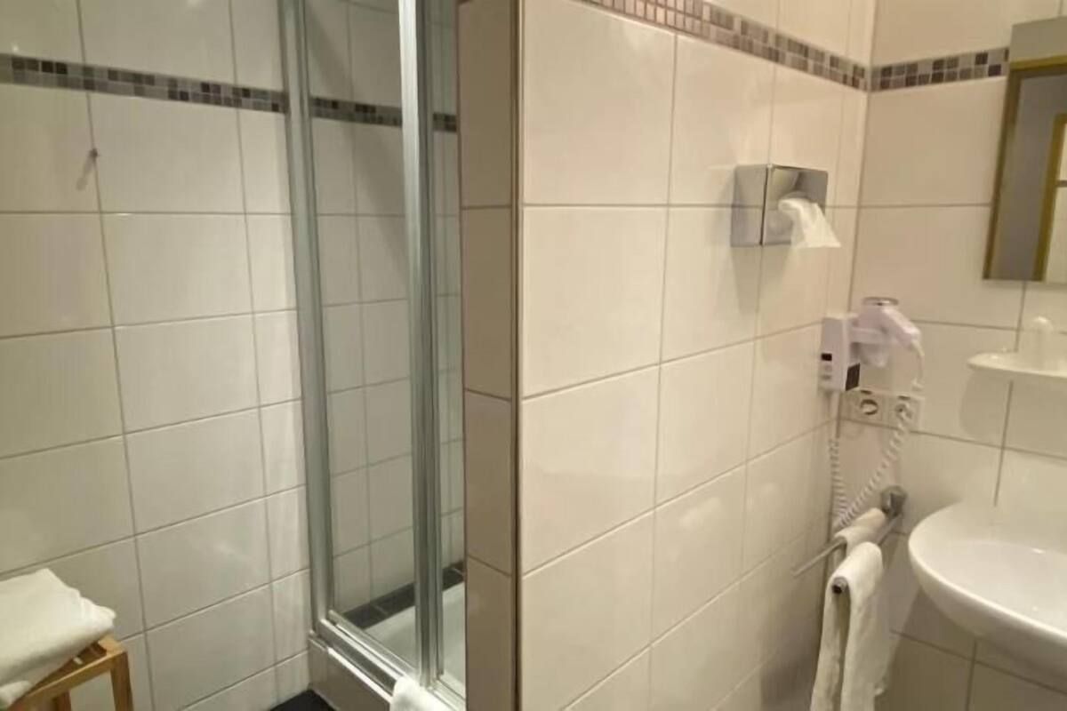 Un baño con cabina de ducha de vidrio, un lavabo y un perchero para toallas.