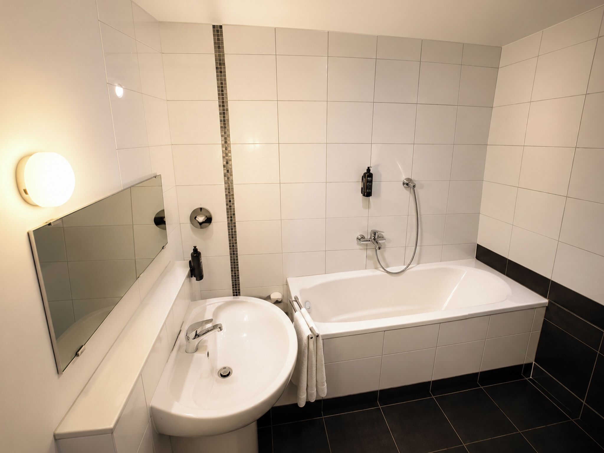A modern bathroom with a bathtub, a sink, and a mirror.