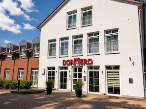 A building with a white facade, multiple windows, and a sign reading 'DORMERO'. - DORMERO Hotel Werther (Werther)
