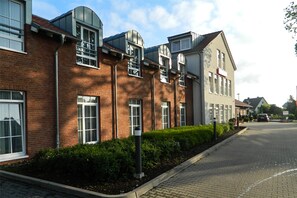 A row of modern brick buildings with large windows and a paved street.