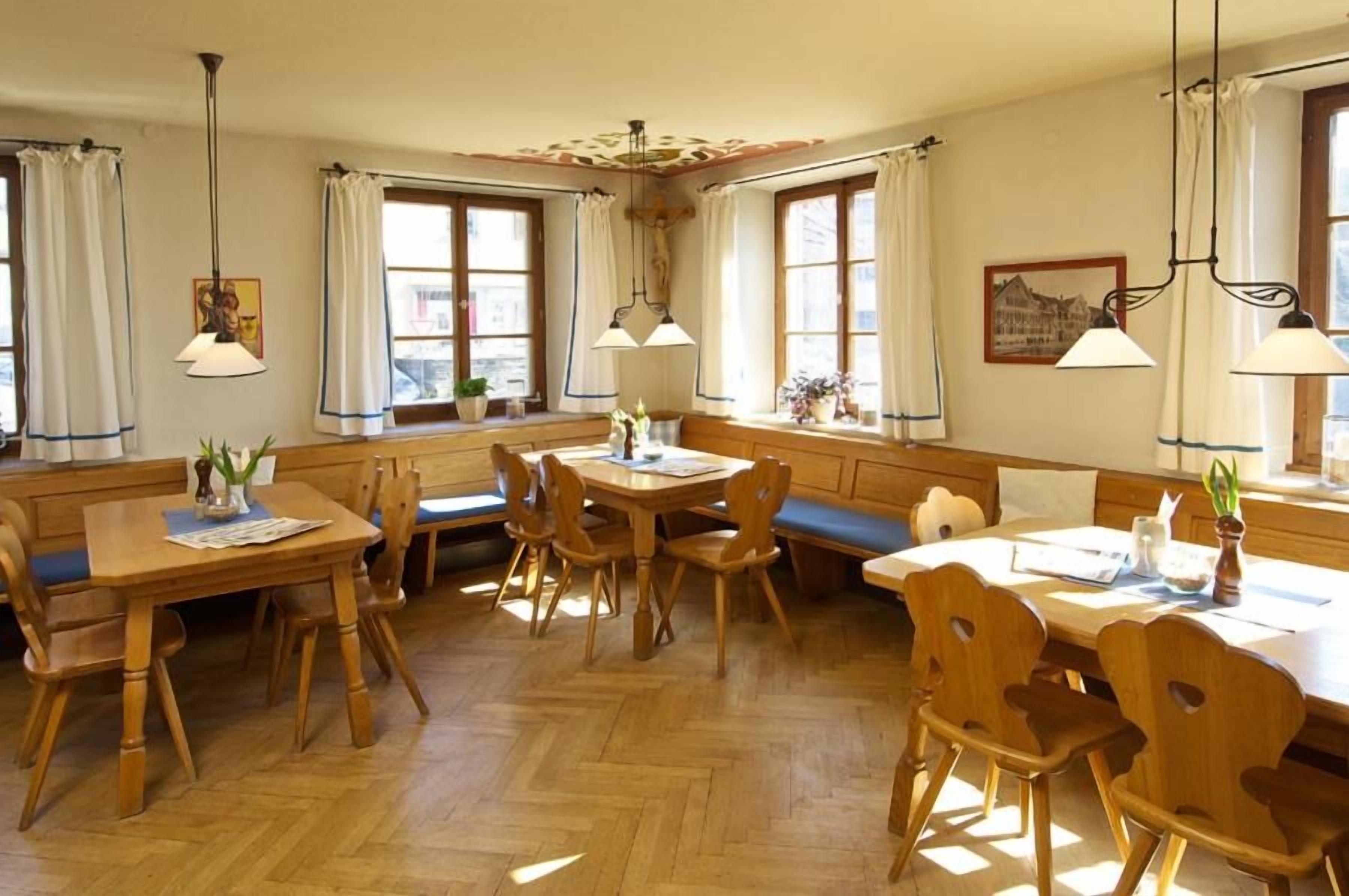 A dining area with wooden furniture, including a table and benches, and a window with curtains.