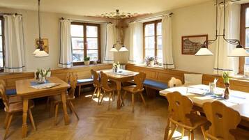 A dining area with wooden furniture, including a table and benches, and a window with curtains.