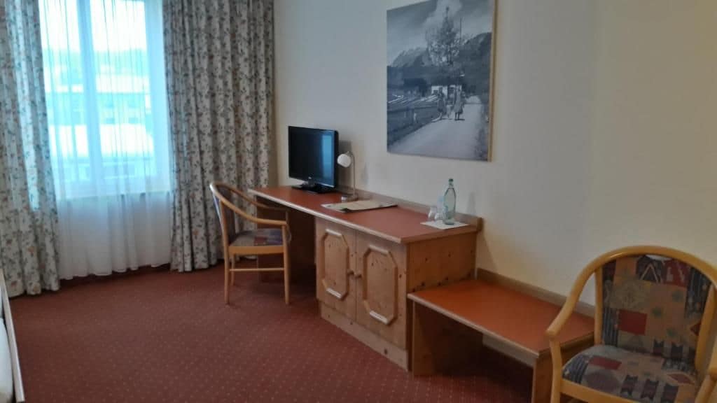 A room with a desk, a chair, a television, and a painting on the wall.