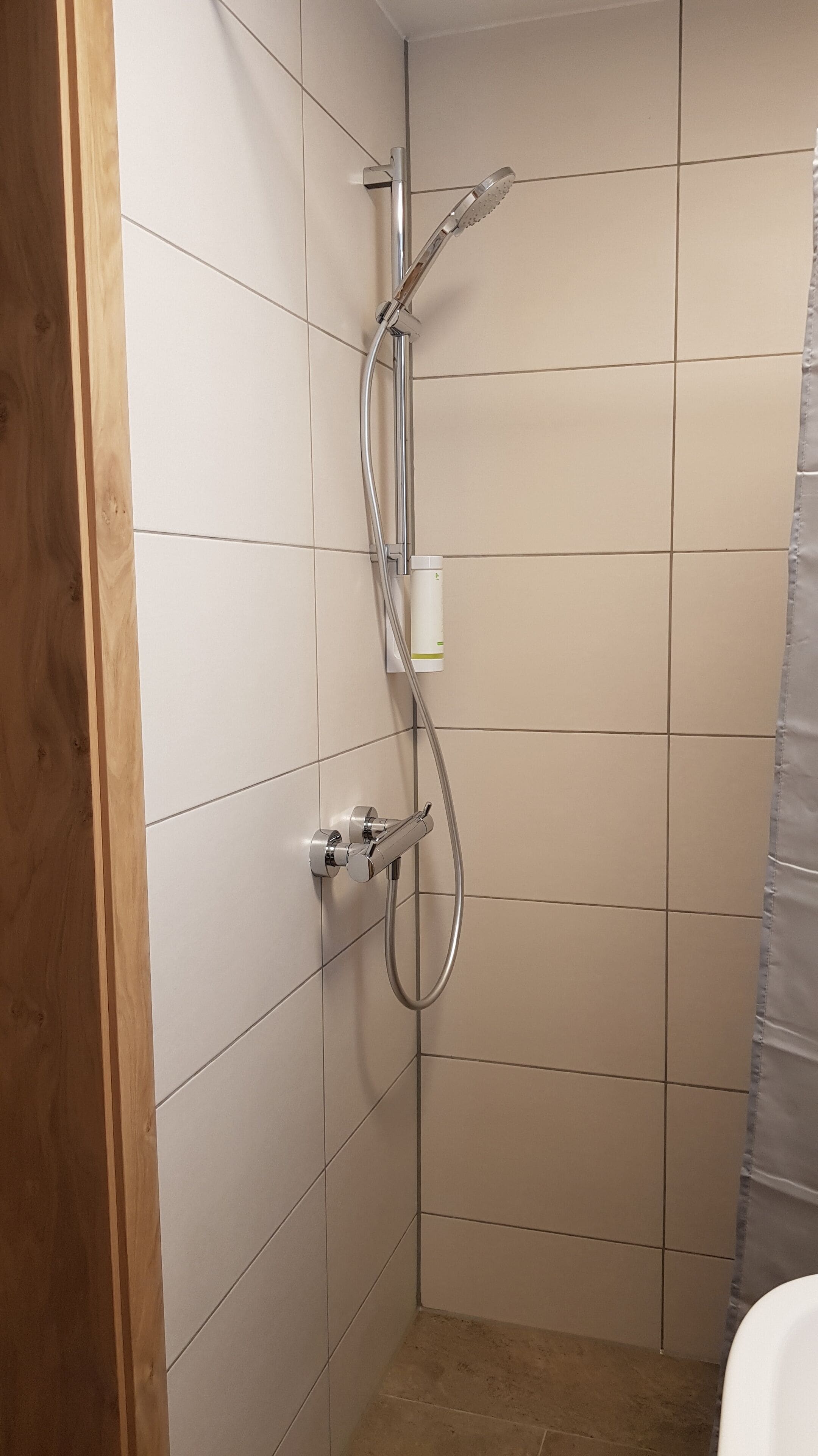Eine Dusche mit Handbrause und Wandarmatur.