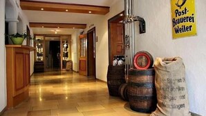 Un pasillo con suelo de madera, barriles y un letrero que dice "Post-Brauerei Weiler".
