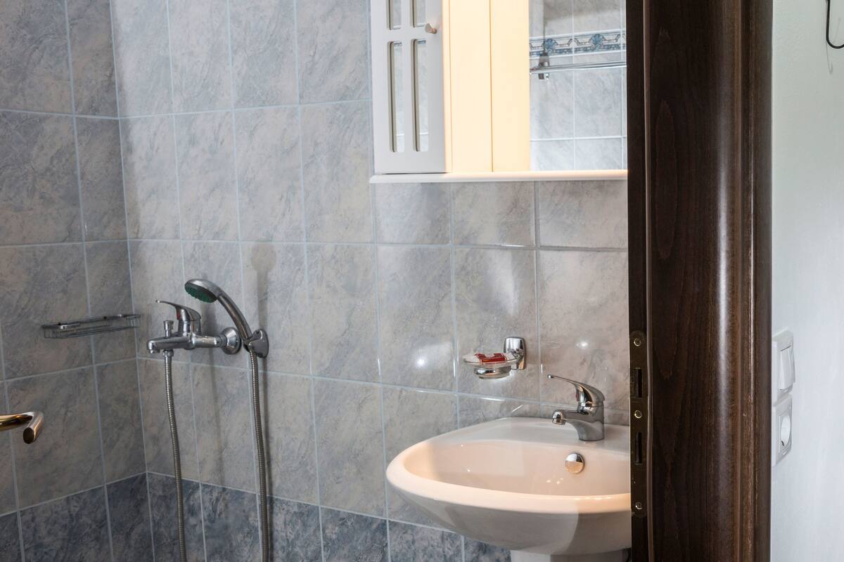 A bathroom with a shower, sink, and mirror.