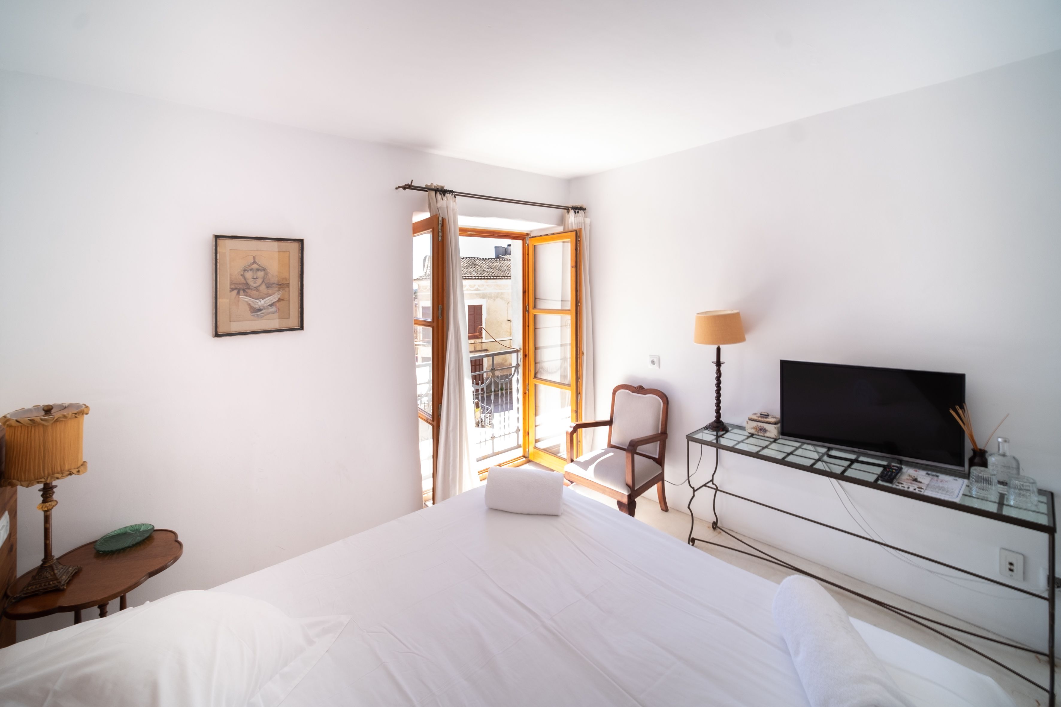 A hotel room with a bed, a chair, a TV, and a window with curtains.