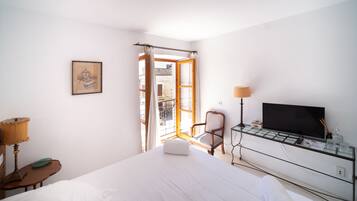 A hotel room with a bed, a chair, a TV, and a window with curtains.