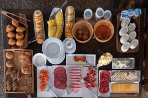 Diversos alimentos como pan, carnes, quesos y frutas dispuestos sobre una mesa.