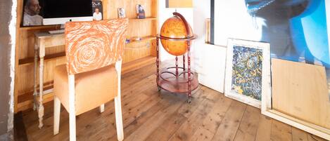 A room with a wooden desk, a computer, a globe on a stand, and artwork on the walls.