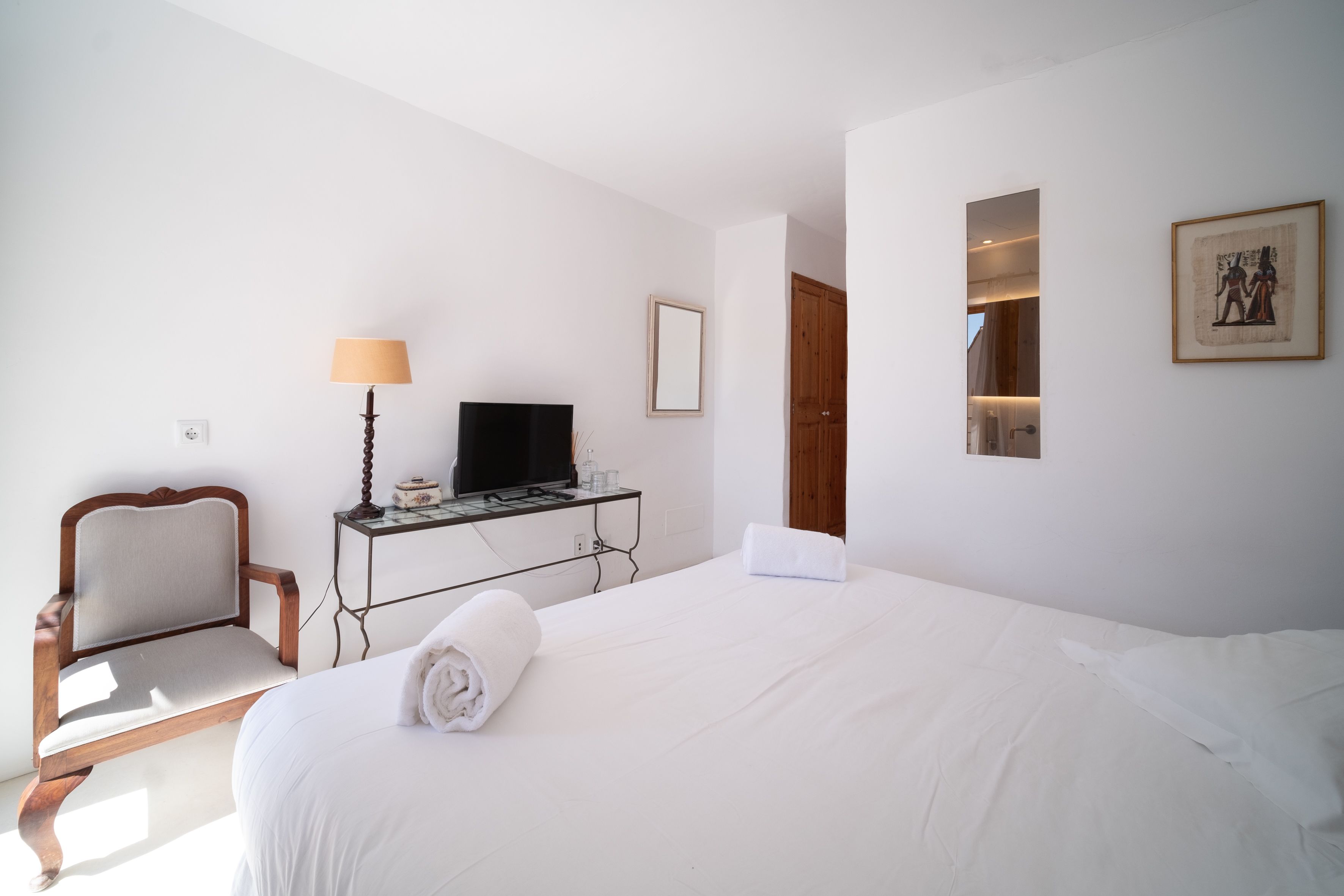 Una habitación de hotel con una cama, un escritorio con televisor, una silla y un cuadro en la pared.