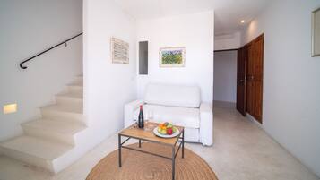 Ein modernes Interieur mit Treppe, weißem Sofa und einem Tisch mit Früchten und Getränken.