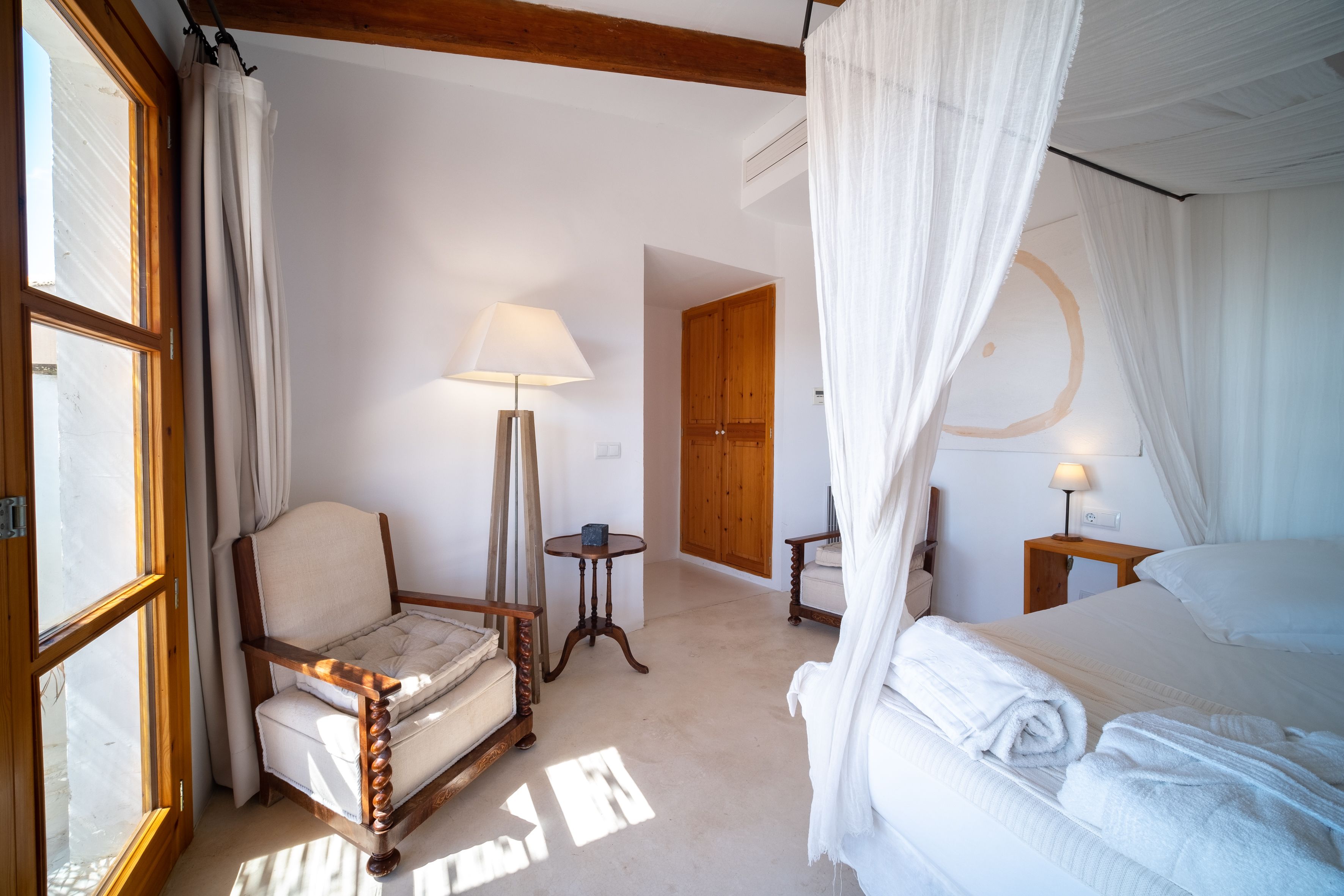 Een slaapkamer met een bed, een stoel, een lamp en een houten deur.