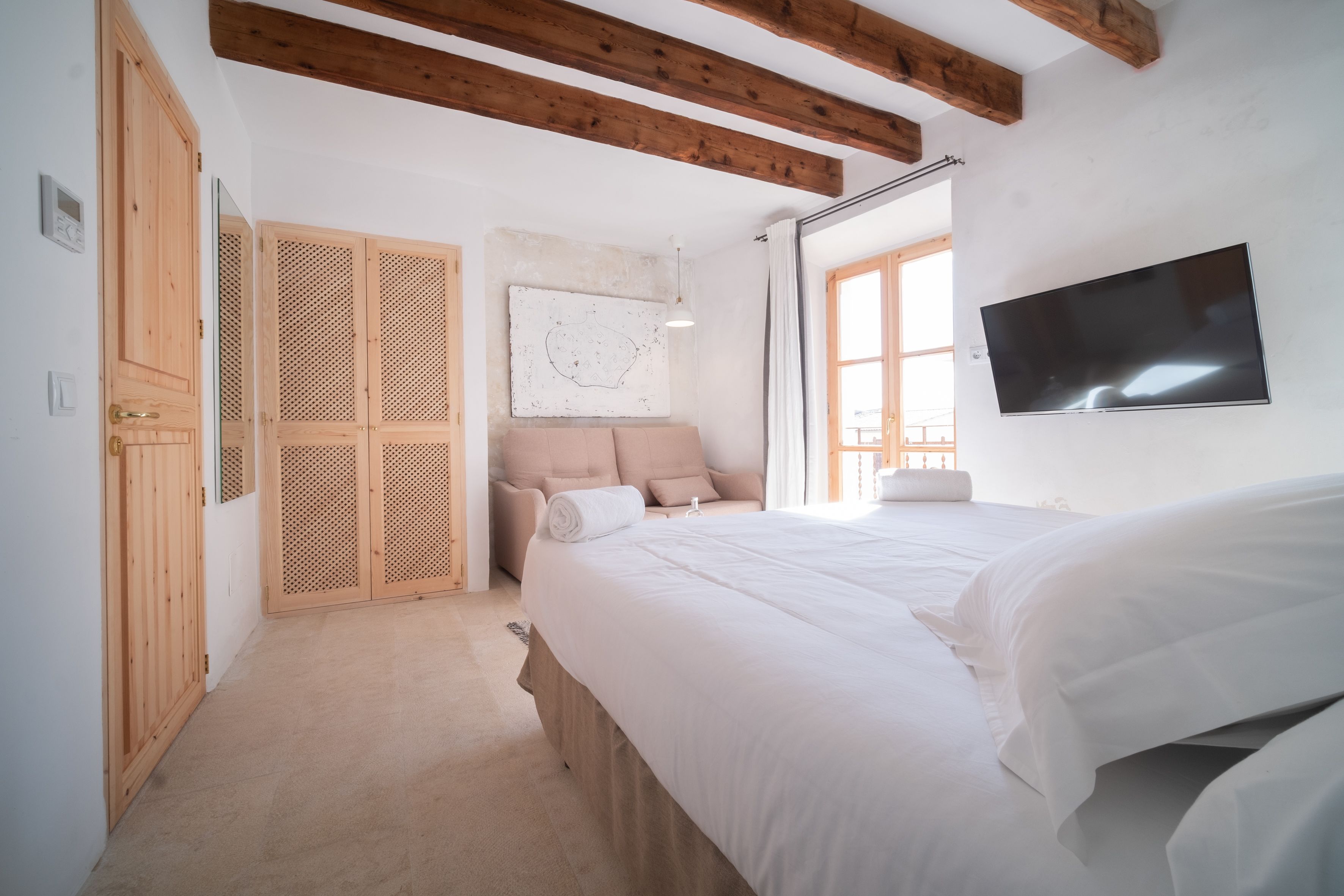 Un dormitorio con cama, armario de madera y televisor en la pared.