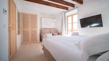 Un dormitorio con cama, armario de madera y televisor en la pared.