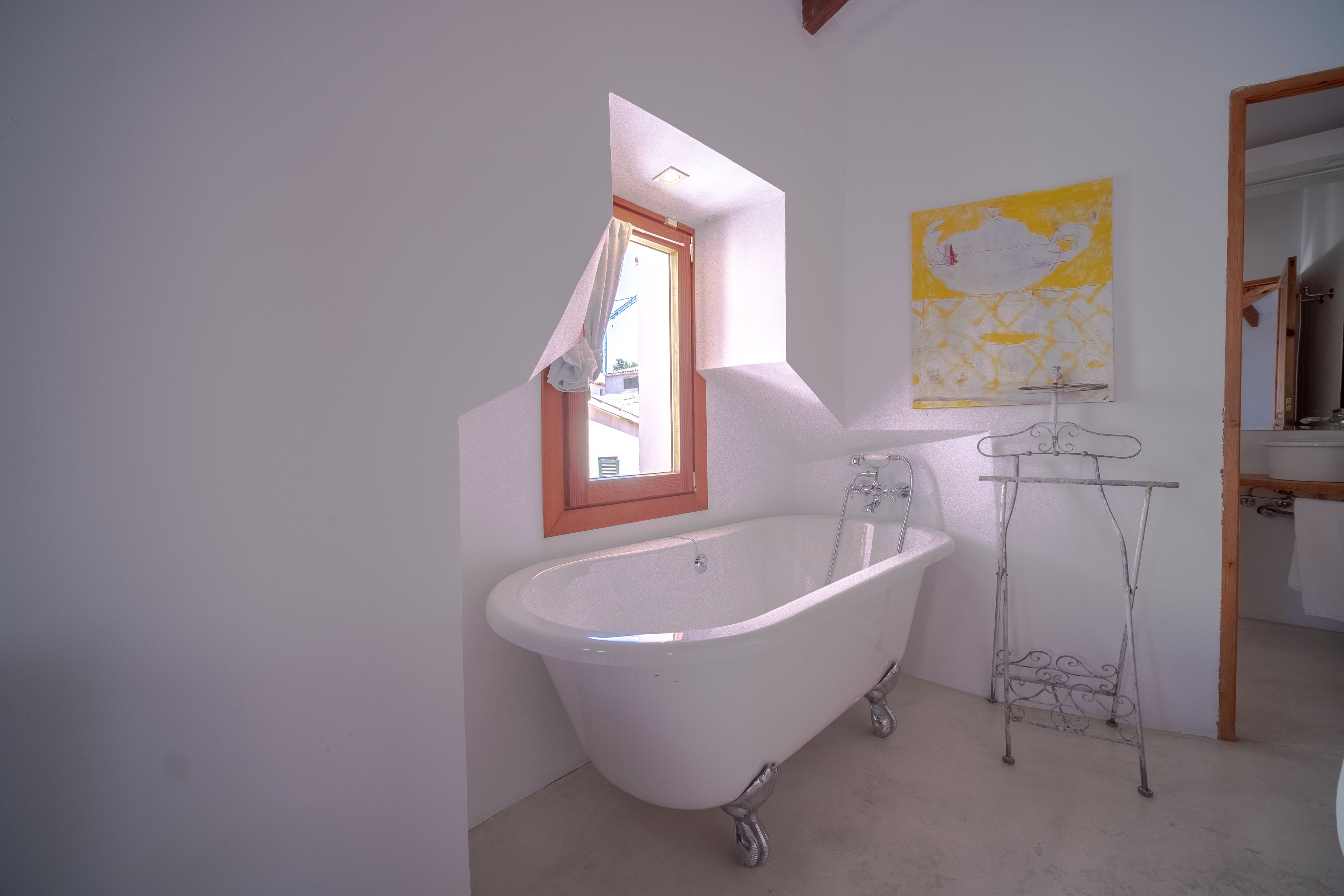 Une salle de bain avec une baignoire sur pieds, une fenêtre, un lavabo et un miroir.
