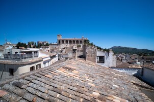 A rooftop with terracotta tiles, a church with a bell tower, and surrounding buildings.
