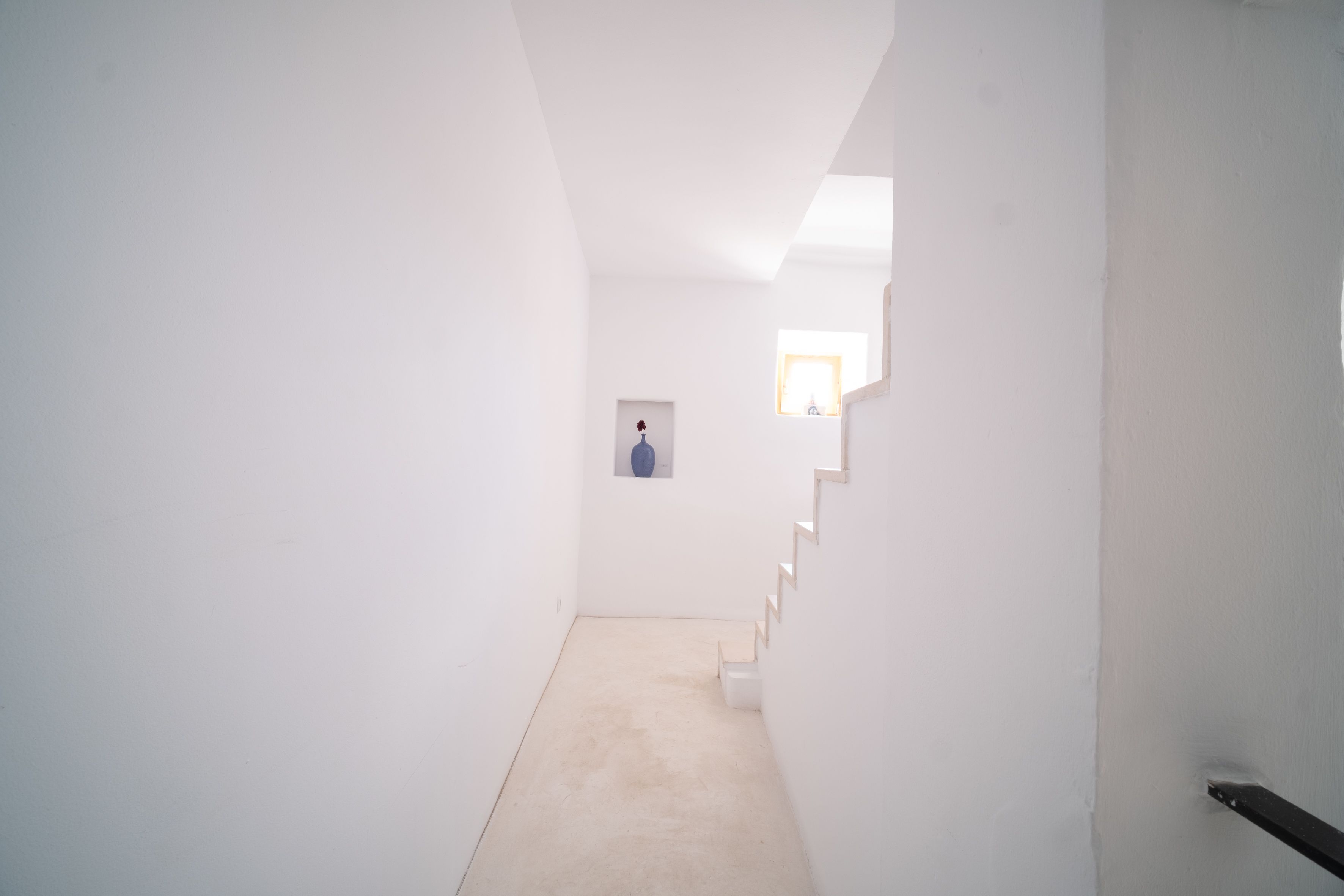 Un couloir étroit aux murs blancs, doté d’un sol recouvert de moquette, mène à une porte située au bout.