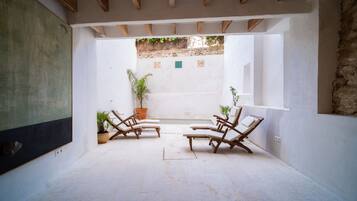 Un espacio habitable de concepto abierto con pared de piedra, vigas de madera en el techo y vista a un jardín.