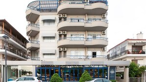A multi-story hotel with balconies, air conditioning units, and a cafe bar on the ground floor. - Olympic Star (Eretria)