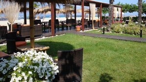 A beachside patio with thatched umbrellas, wicker furniture, and a view of the beach. - Olympic Star (Eretria)