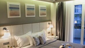 A modern hotel room with a large bed, bedside tables with lamps, a view of the balcony, and artwork on the wall. - Olympic Star (Eretria)