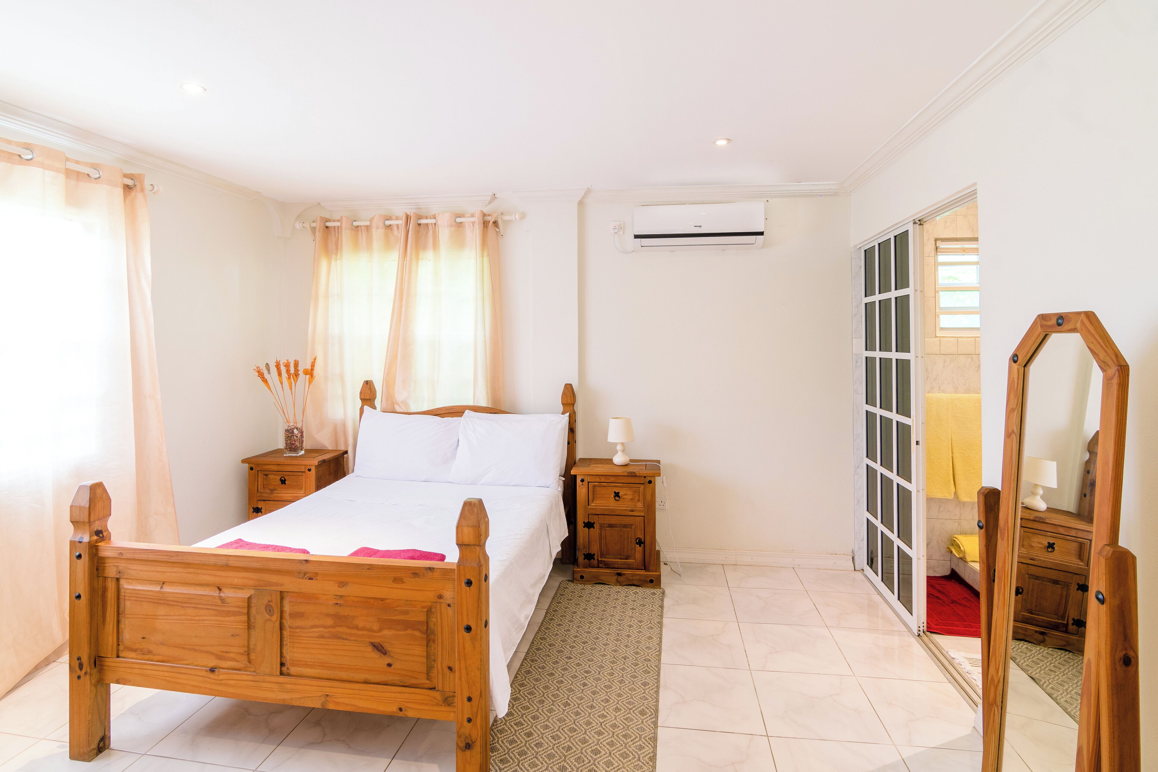 Une chambre à coucher avec un lit en bois, des tables de chevet, un miroir et un appareil de climatisation.