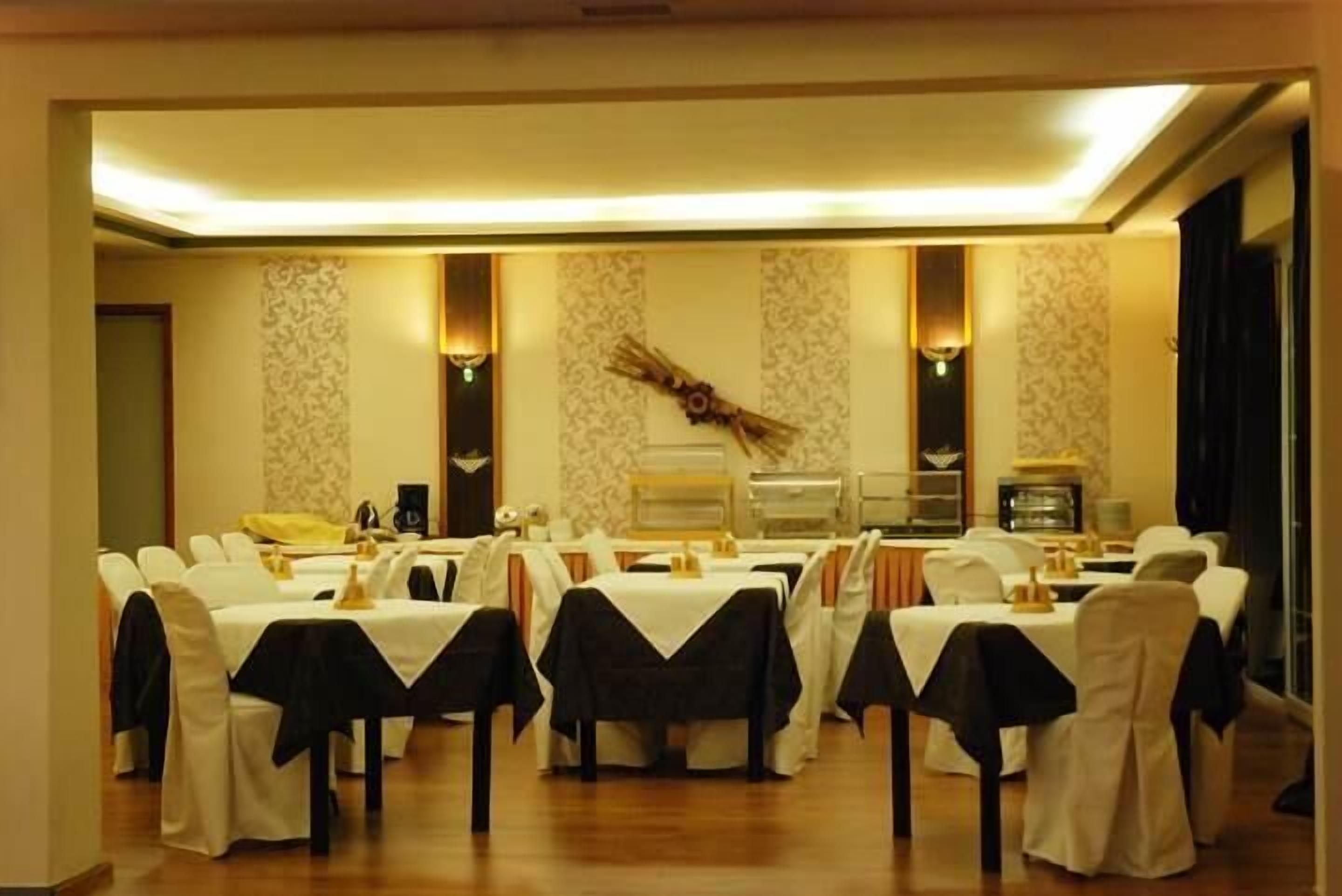 A banquet hall with multiple round tables, each covered with a white tablecloth and black chair covers.