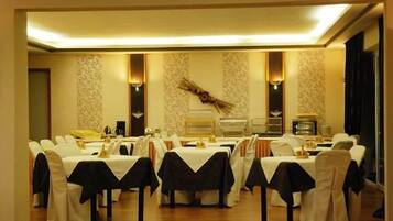 A banquet hall with multiple round tables, each covered with a white tablecloth and black chair covers.