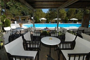 An outdoor patio with tables and chairs, a pool, and umbrellas.
