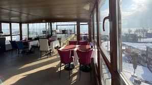 A restaurant with large windows offering a city view, tables and chairs arranged for dining, and a wooden ceiling. - Spinel Hotel (Istanbul)