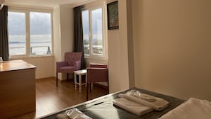 A hotel room with a bed, a desk, two chairs, a small table, and a view of the sea. - Spinel Hotel (Istanbul)