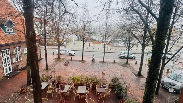 An outdoor seating area with tables and chairs, surrounded by trees and a brick pathway. - Hotel Diamant (Wedel)