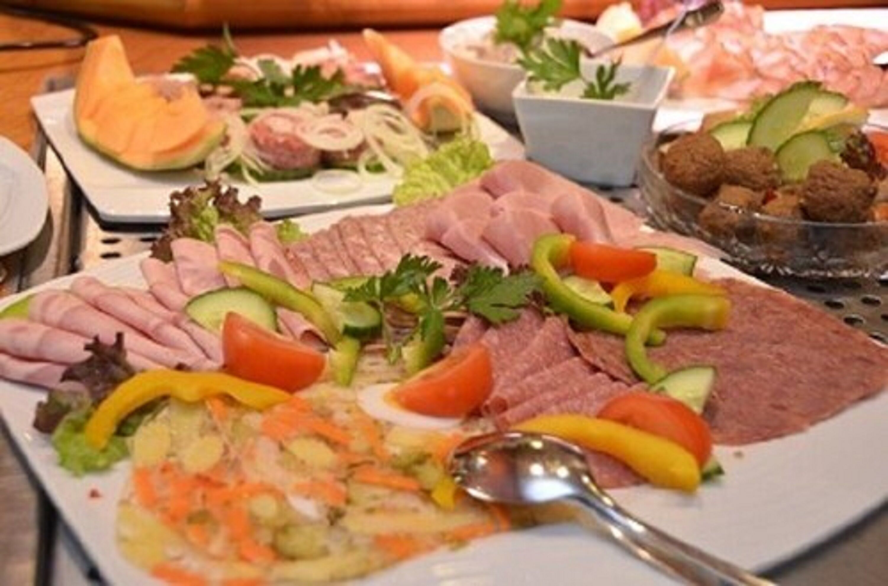 Diversa variedad de alimentos, incluyendo carnes cortadas, verduras y un bol de albóndigas.